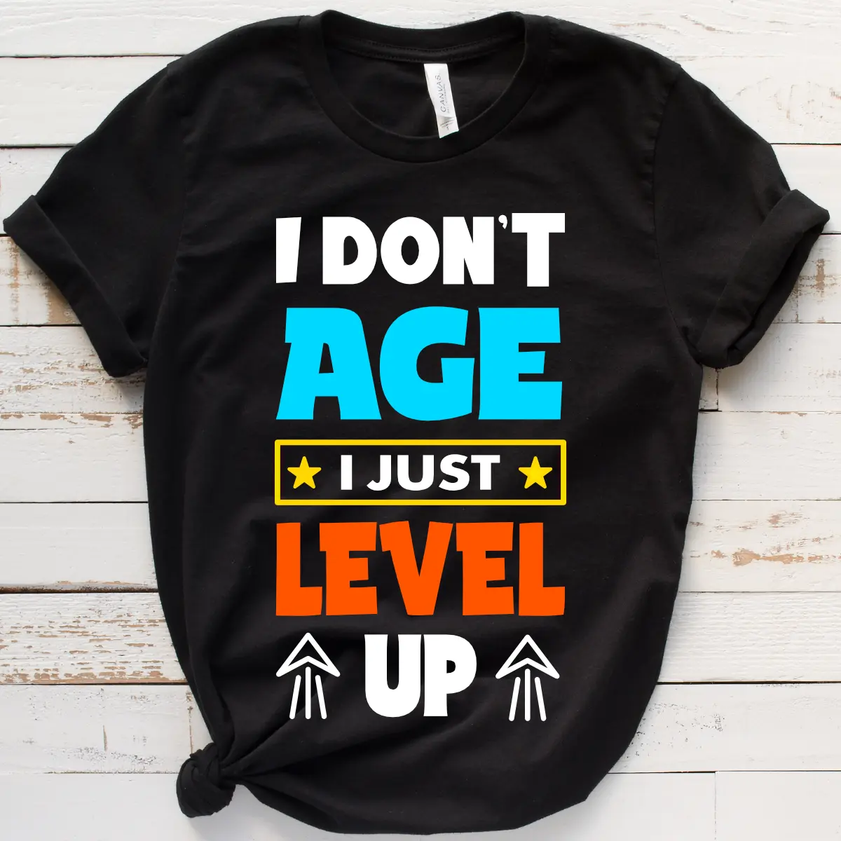 Black t-shirt with bold colorful text saying "I Don't Age I Just Level Up," a perfect birthday gift for gamers.